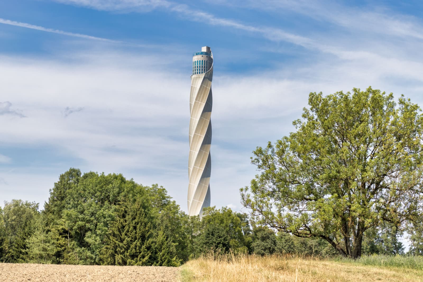 Ausflug Thyssenkrupp Testturm Rottweil
Der Thyssenkrupp Testturm ist ein moderner Forschungsturm für Aufzugstechnologie. Hier testet das Unternehmen neue Aufzüge unter realistischen Bedingungen – zum Beispiel besonders schnelle oder innovative Systeme ohne klassische Seile.
Einzigartig ist der Turm vor allem durch seine Höhe von rund 246 Metern und seine futuristische Architektur mit einer halbtransparenten Textilfassade, die sich je nach Licht verändert. Außerdem besitzt er Deutschlands höchste Besucherplattform, von der aus man einen beeindruckenden Blick über den Schwarzwald und die Schwäbische Alb hat.